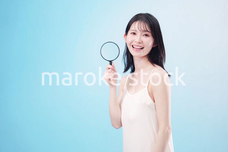 虫眼鏡を持つ若い女性・ビューティーイメージ