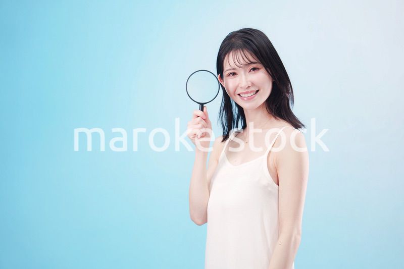 虫眼鏡を持つ若い女性・ビューティーイメージ