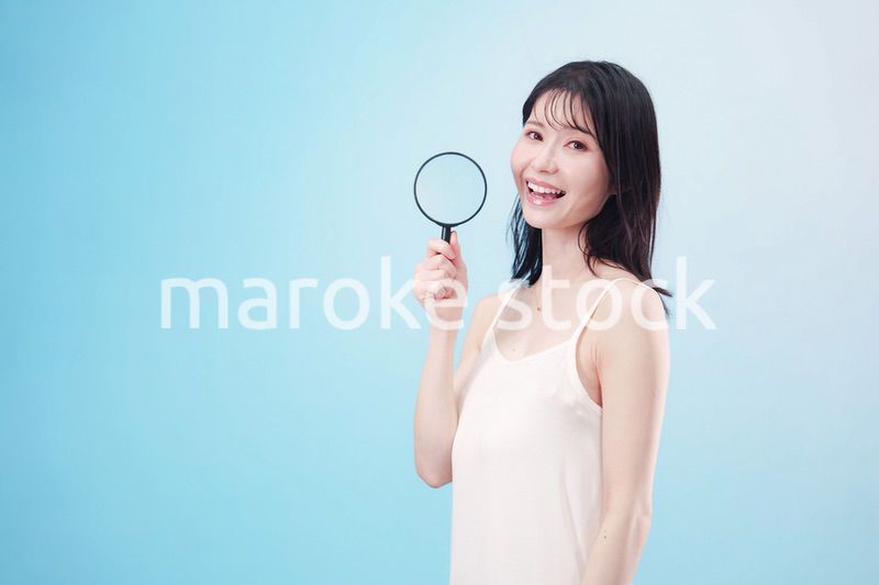 虫眼鏡を持つ若い女性・ビューティーイメージ