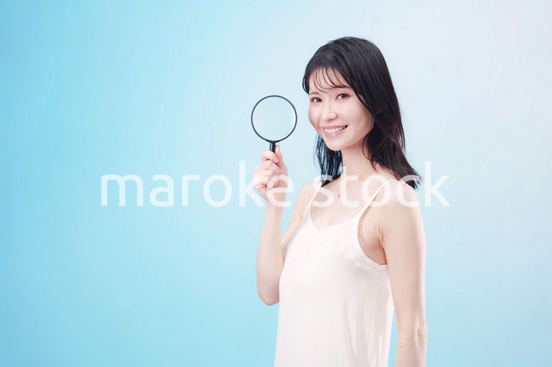 虫眼鏡を持つ若い女性・ビューティーイメージ