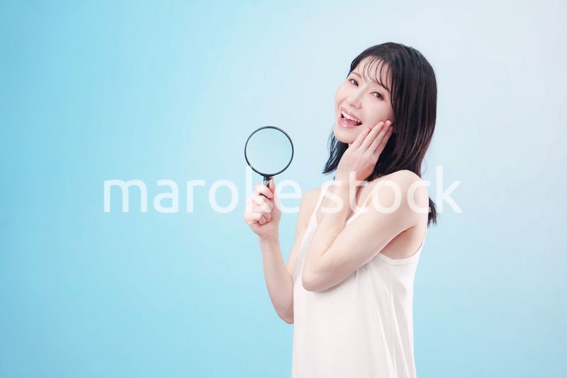 虫眼鏡を持つ若い女性・ビューティーイメージ