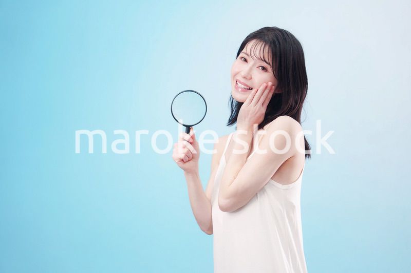 虫眼鏡を持つ若い女性・ビューティーイメージ