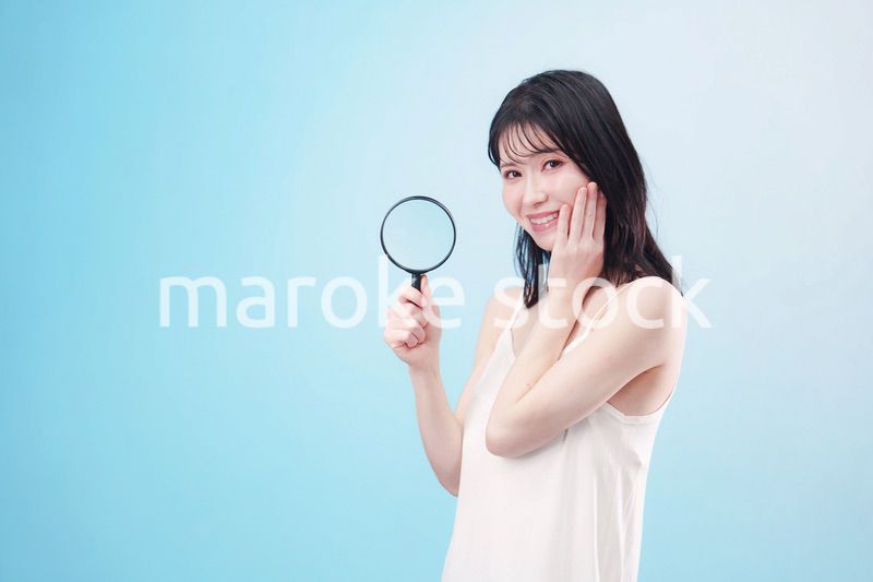 虫眼鏡を持つ若い女性・ビューティーイメージ