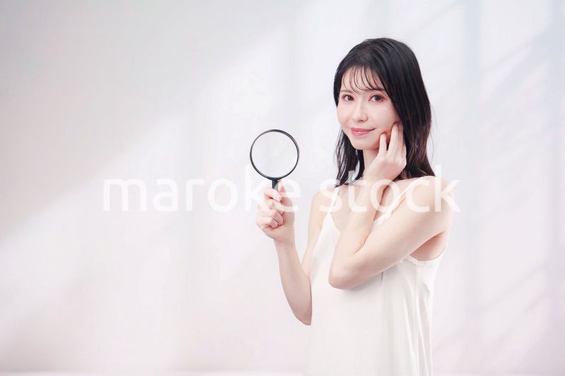 虫眼鏡を持つ若い女性・ビューティーイメージ