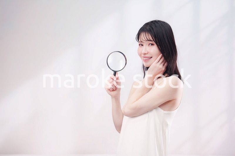 虫眼鏡を持つ若い女性・ビューティーイメージ