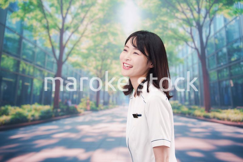 白衣を着て笑顔で外を歩く医療従事者の若い女性