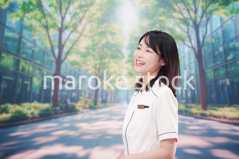 白衣を着て笑顔で外を歩く医療従事者の若い女性