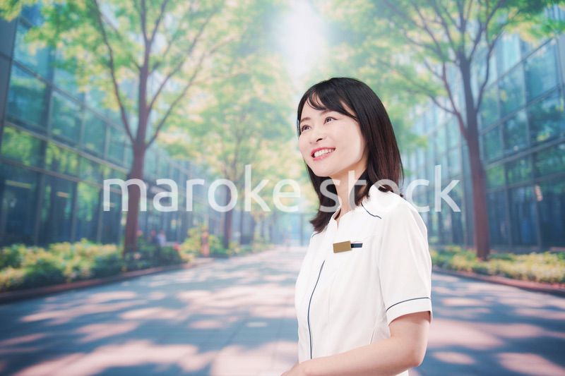 白衣を着て笑顔で外を歩く医療従事者の若い女性