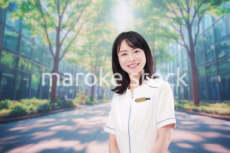 白衣を着て笑顔で外を歩く医療従事者の若い女性