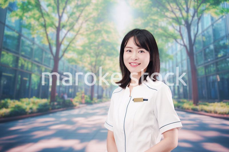 白衣を着て笑顔で外を歩く医療従事者の若い女性