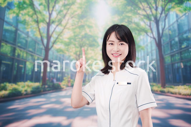 白衣を着て笑顔で外を歩く医療従事者の若い女性