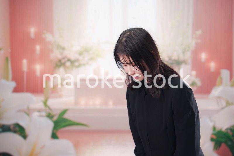 お葬式・お通夜で喪服を着て合掌をする若い女性