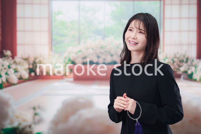お葬式で喪服を着て数珠を持つ若い女性