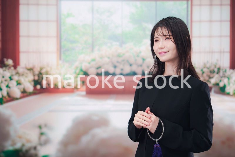 お葬式で喪服を着て数珠を持つ若い女性