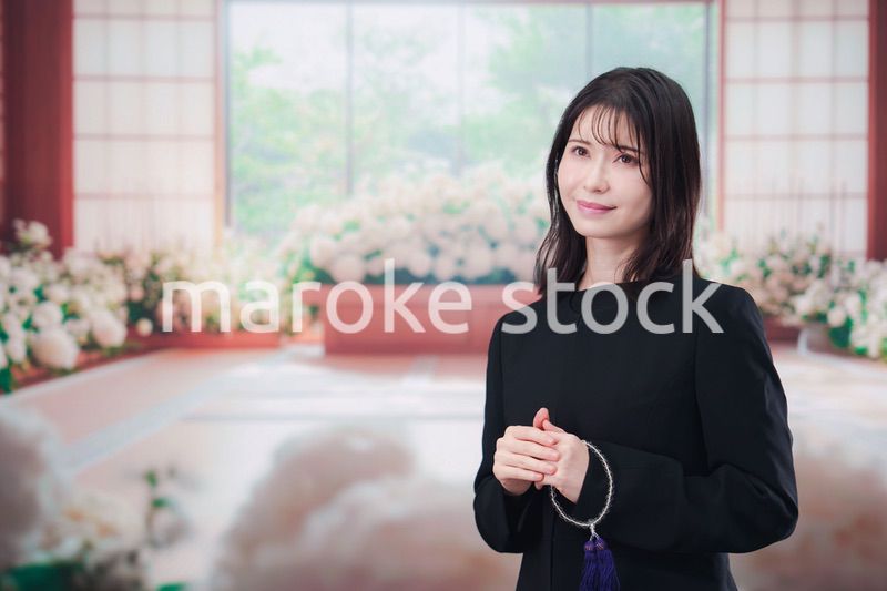 お葬式で喪服を着て数珠を持つ若い女性