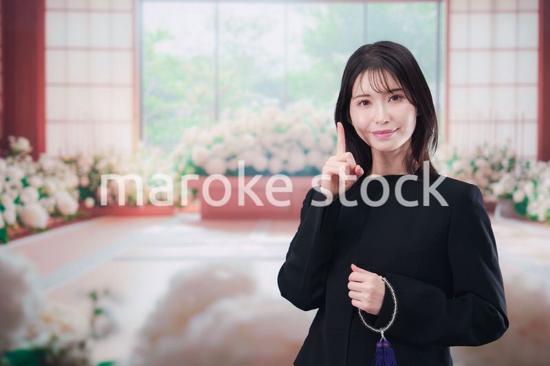 お葬式で喪服を着て数珠を持つ若い女性