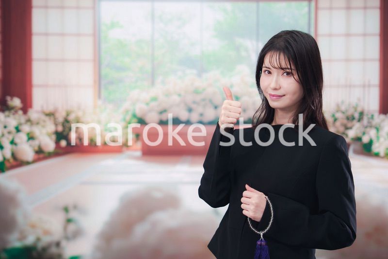 お葬式で喪服を着て数珠を持つ若い女性