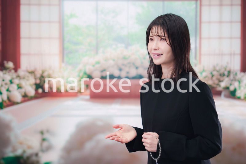 お葬式で喪服を着て数珠を持つ若い女性