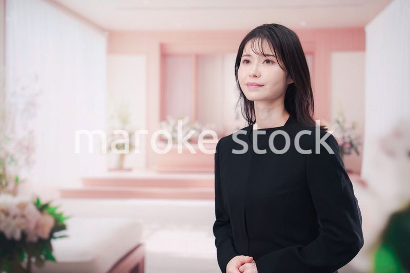 お葬式で喪服を着て数珠を持つ若い女性