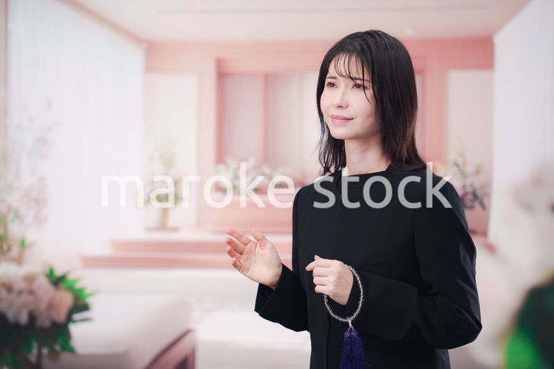 お葬式で喪服を着て数珠を持つ若い女性