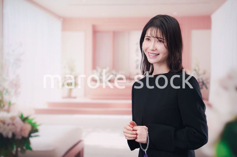 お葬式で喪服を着て数珠を持つ若い女性