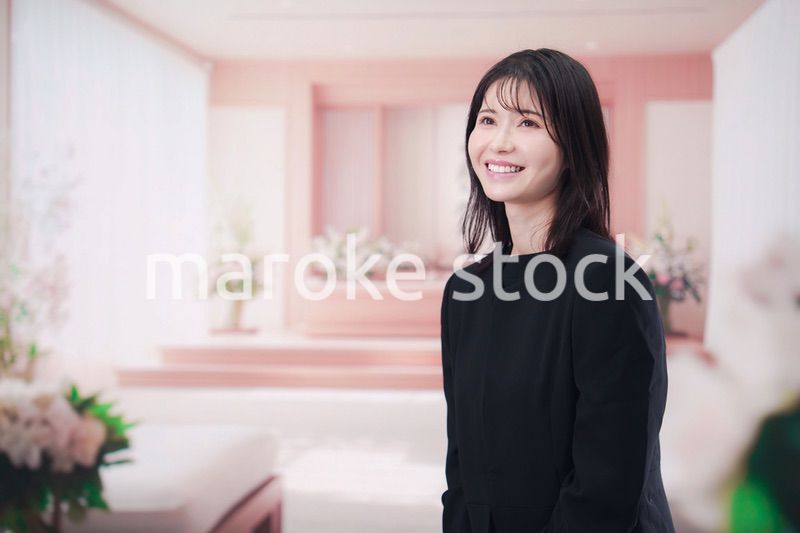 お葬式で喪服を着て数珠を持つ若い女性