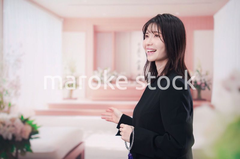 お葬式で喪服を着て数珠を持つ若い女性