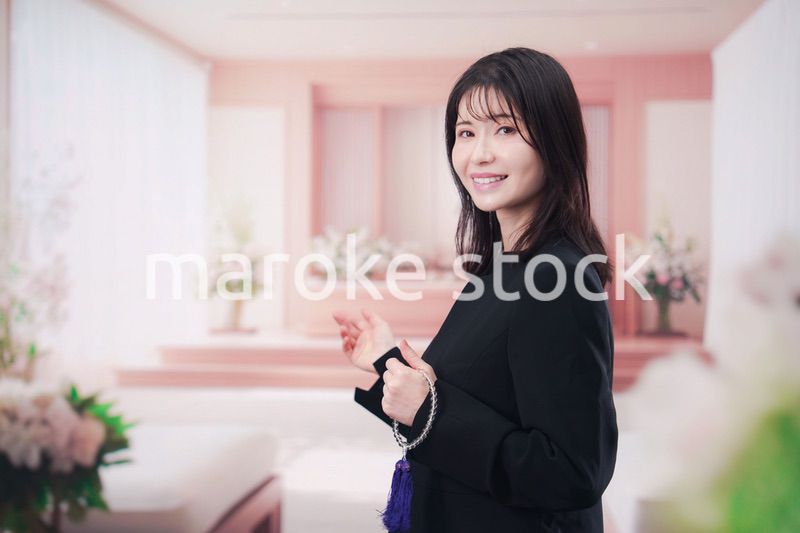 お葬式で喪服を着て数珠を持つ若い女性