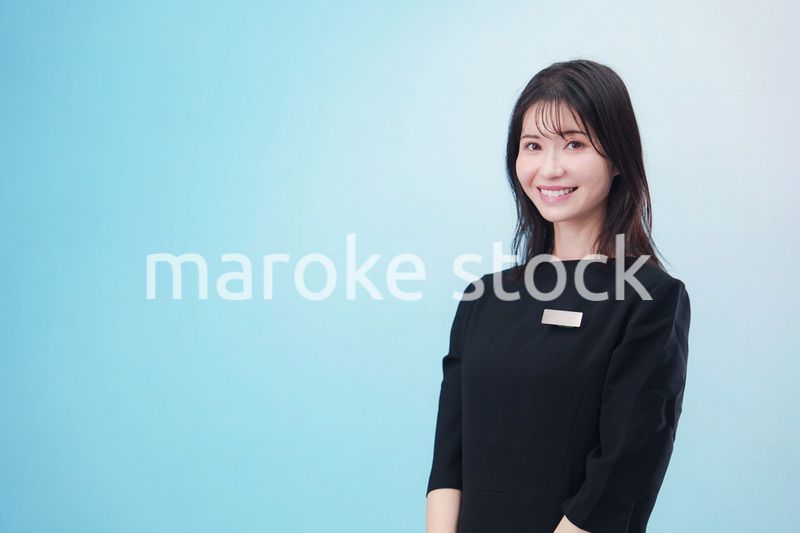 黒い服に名札をつけた笑顔のスタッフ（水色背景）