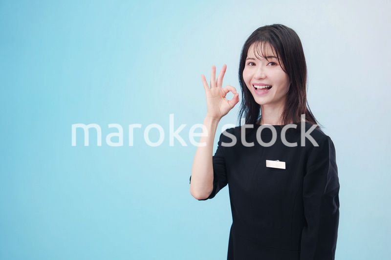 黒い服に名札をつけた笑顔のスタッフ（水色背景）