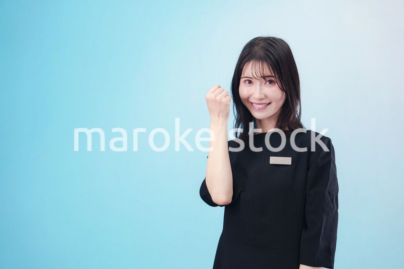 黒い服に名札をつけた笑顔のスタッフ（水色背景）