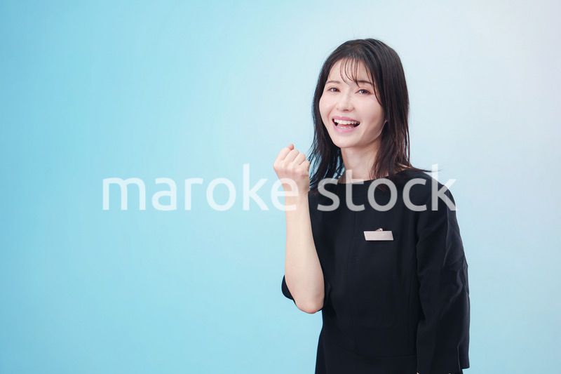 黒い服に名札をつけた笑顔のスタッフ（水色背景）