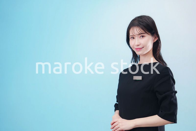 黒い服に名札をつけた笑顔のスタッフ（水色背景）