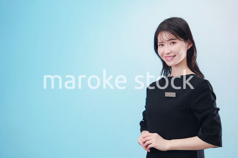 黒い服に名札をつけた笑顔のスタッフ（水色背景）