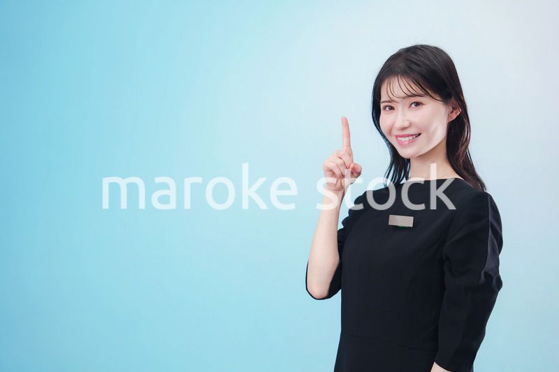 黒い服に名札をつけた笑顔のスタッフ（水色背景）