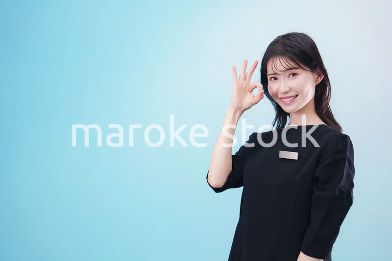 黒い服に名札をつけた笑顔のスタッフ（水色背景）