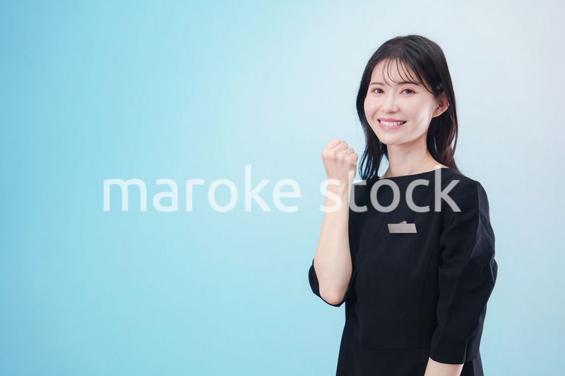 黒い服に名札をつけた笑顔のスタッフ（水色背景）