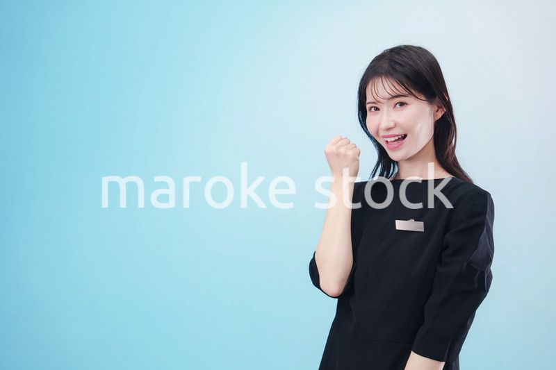 黒い服に名札をつけた笑顔のスタッフ（水色背景）