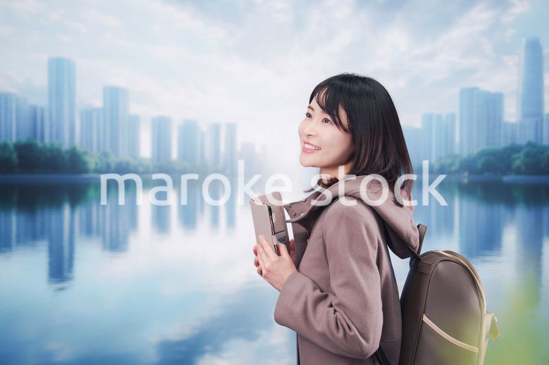 コートを着てスマホを使いながら外を歩く若い女性