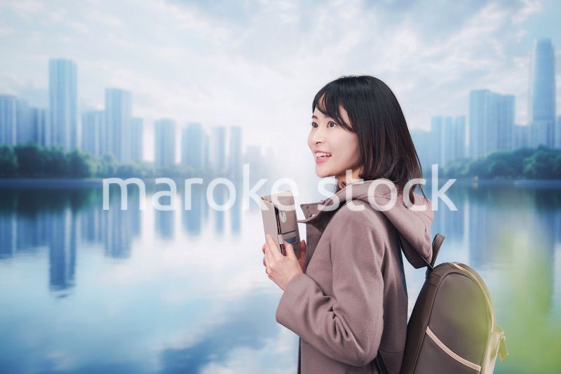 コートを着てスマホを使いながら外を歩く若い女性