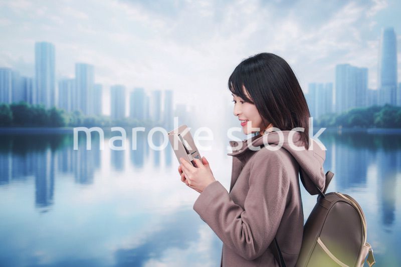 コートを着てスマホを使いながら外を歩く若い女性