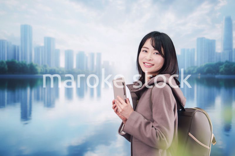 コートを着てスマホを使いながら外を歩く若い女性