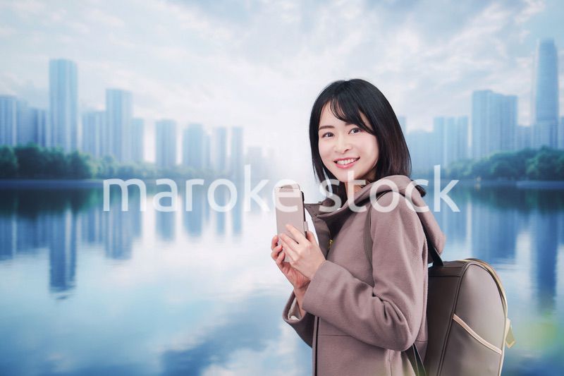 コートを着てスマホを使いながら外を歩く若い女性