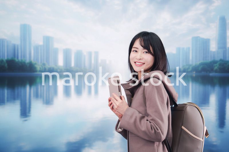 コートを着てスマホを使いながら外を歩く若い女性