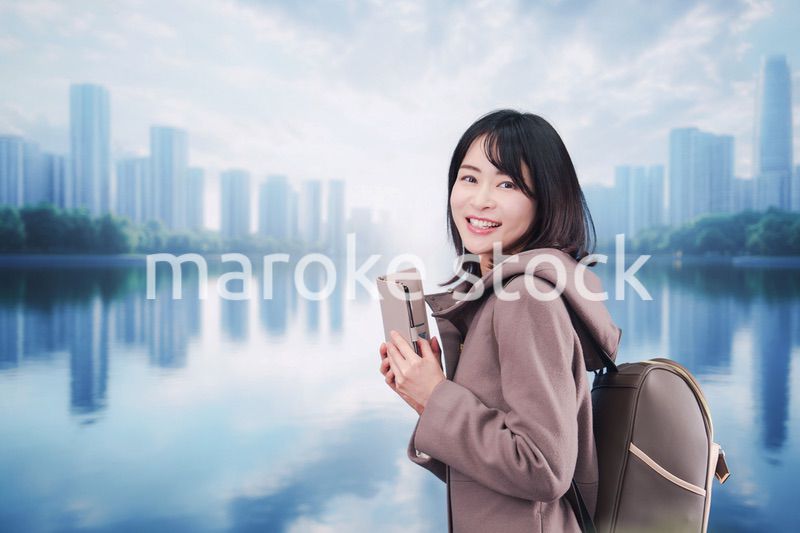 コートを着てスマホを使いながら外を歩く若い女性