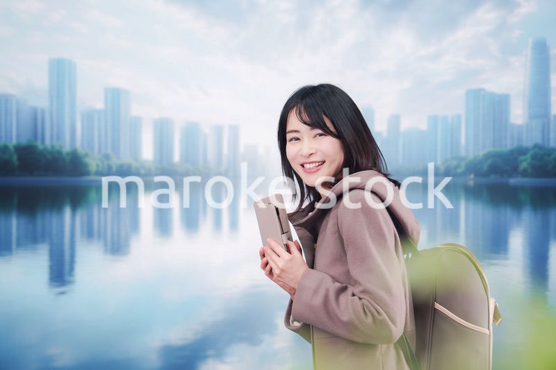 コートを着てスマホを使いながら外を歩く若い女性