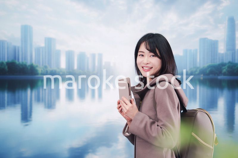 コートを着てスマホを使いながら外を歩く若い女性