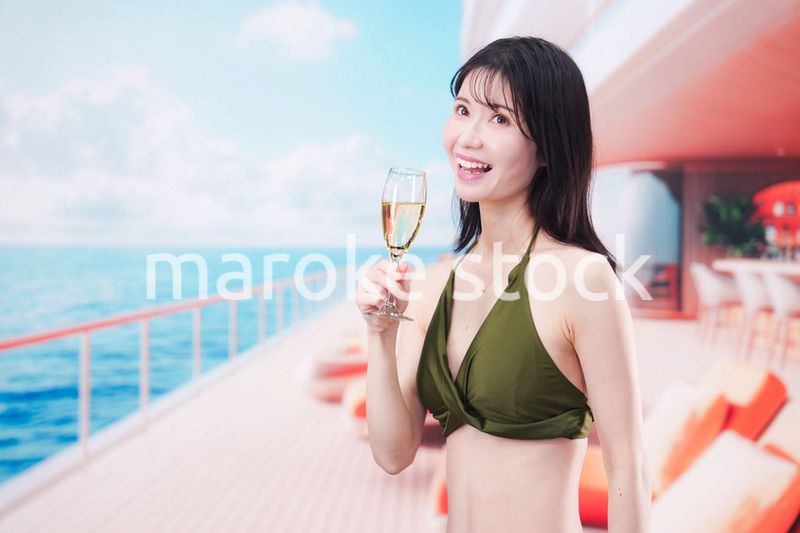 クルーズ船で水着を着てスパークリングワインを飲む若い女性