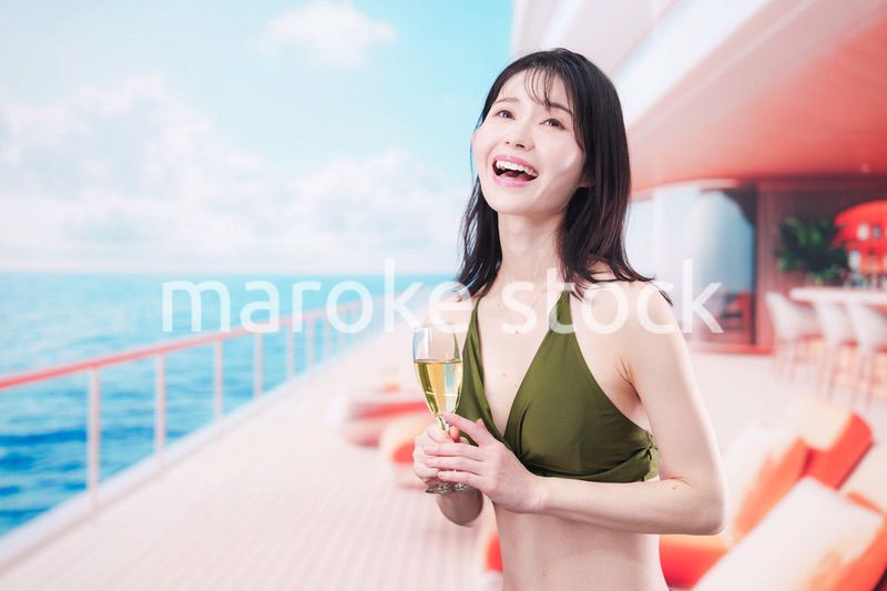 クルーズ船で水着を着てスパークリングワインを飲む若い女性