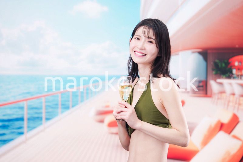 クルーズ船で水着を着てスパークリングワインを飲む若い女性